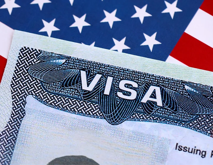 Close-up of a United States visa document with American flag background.